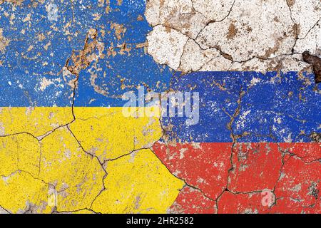 Closeup, flags of Ukraine against Russia on a cracked brick wall background. Concept of crisis of war and political conflicts between nations.  Stock Photo