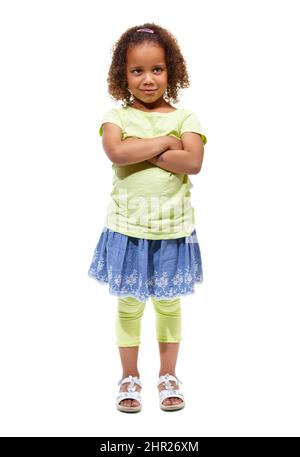 Shes got plenty of sass. Cute little african american girl standing against a white background with her arms folded. Stock Photo