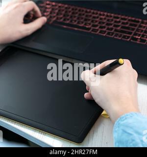 designer working on a professional tablet with a pen, Close-up of a man's hand holding a graphic pen for drawing Stock Photo