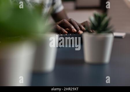 Close up of african american student hand typing project information on computer keyboard. Freelancer man attending at financial lesson during online webinar working remote from home Stock Photo
