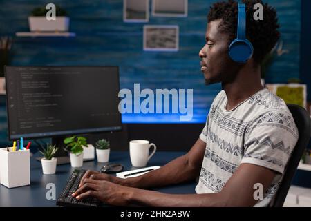Young it hacker programming software for website security typing html code developing application. Businessman wearing headphones working at infographics javascript. Remote work from home Stock Photo