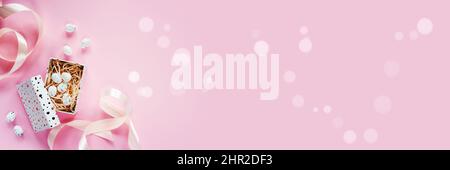 Easter banner with Easter eggs in a gift box with pink ribbons on pink background Stock Photo