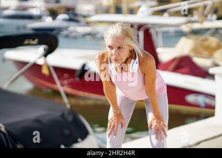Senior woman in fitness clothing taking a break during exercise. Stock Photo