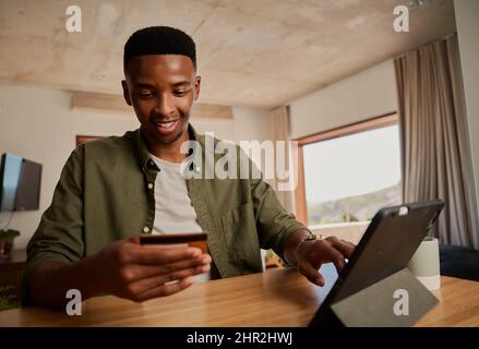 Happy young adult black male using electronic tablet to make online purchase.  Stock Photo