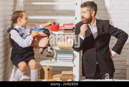 Schoolgirl studying in classroom with teacher. Father explaining homework to his daughter at home. Doing homework with dad. Stock Photo