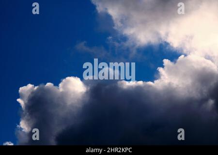 Cumulus clouds against a blue sky darl and moody. Stock Photo