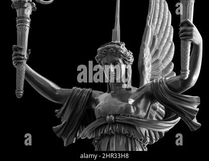 Sculpture of a Winged Victory goddess Nika. Statue of a beautiful holy angel with wings holding a torchs isolated at black background with clipping Stock Photo