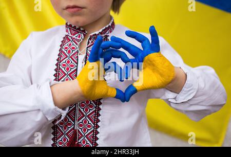 Children against war. Russia's invasion of Ukraine, request for help from world community. child against background of Ukrainian flag with hands in sh Stock Photo