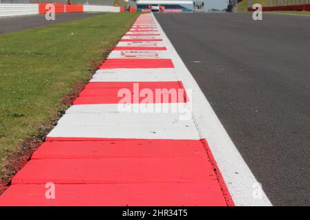 red and white curb on the edge of a long straight down a racing track Stock Photo