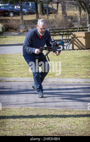 A man filming with a still camera. In a park in Queens, New York on a mild winter day. Stock Photo