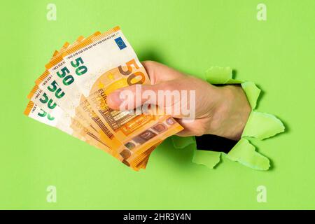 Businessman breaking through green paper with money in hand, closeup Stock Photo