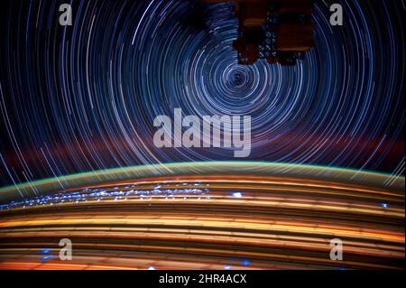 Earth horizon glows, Stars in motion background, long-exposure satellite photos from space, colorful rings. Elements of this image furnished by NASA. Stock Photo