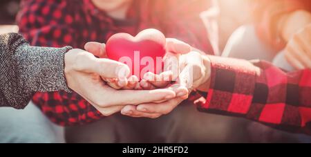 Mother, father and their child holding a heart symbol in their hands Stock Photo