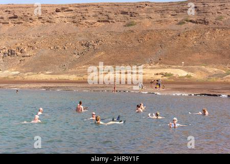Tourists floating in salt evaporation ponds in crater lake, Pedra de Lume, Sal (IIha do Sal), República de Cabo (Cape Verde) Stock Photo