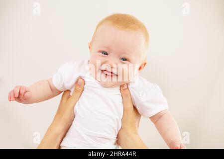 Shes flying. An adorable baby girl being lifted into the air by her mother. Stock Photo