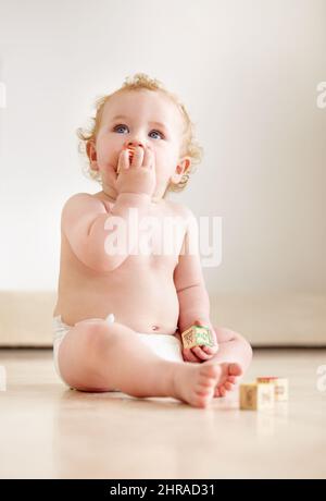 Filled with curiousity and wonder. Cute baby boy looking up curiously while sitting on the floor. Stock Photo