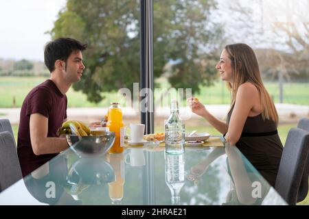Young couple having breakfast in the living room of their house near the garden Stock Photo