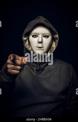 hacker with white mask with hand pointing to the camera. Stock Photo