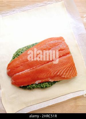 Overhead view of a salmon fillet with spinach and mushroom on pastry being prepared Stock Photo