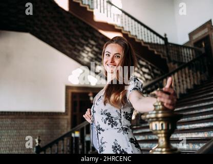 Beautiful and smiling carefree woman descending some stairs of a Palace sightseeing in Europe Stock Photo