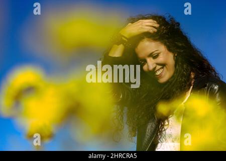 Portrait of a happy Hispanic female in a rapeseed field Stock Photo