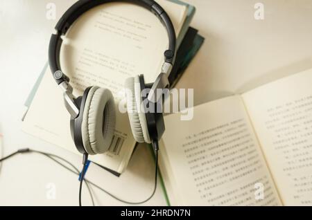 Closeup of pair of headphones on a stack of books with a blurry background Stock Photo