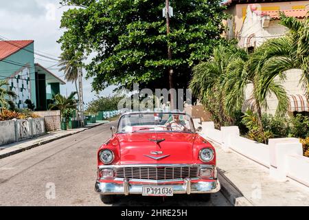 Man sitting in red and white retro 1957 Chevrolet car on street of resort town. Stock Photo