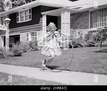 1950s GIRL IN DRESS ON SUBURBAN SIDEWALK PLAYING WITH A HULA HOOP - j7987 HAR001 HARS WALK SIDE JUMP NOSTALGIC HULA COMMUNITY SUBURBAN PLASTIC SIDEWALK OLD TIME NOSTALGIA MOVING OLD FASHION 1 JUVENILE HOOP BLOND ROUND ROLLING YOUNG ADULT CIRCLE MOVEMENT JOY FEMALES HOUSES MOTION HEALTHINESS HOME LIFE PEOPLE CHILDREN FULL-LENGTH PHYSICAL FITNESS ADOLESCENT DAUGHTERS ICON RESIDENTIAL BUILDINGS AMERICANA MOVE B&W SPLIT NEIGHBORHOOD CHALLENGE HOOPS RECREATION HOMES PRETEEN SMILES TWIST FAD CIRCULAR COORDINATION LONE RESIDENCE TEENAGED HULA HOOP HULA HOOPS HULA-HOOP HULA-HOOPS HOOP ROLLING Stock Photo