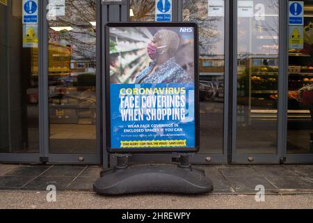 Cookham, Berkshire, UK. 24th February, 2022. Although no longer a legal requirement, a Coronavirus Face Coverings When Shopping sign asks customers to continue to wear face coverings before entering a local general store in Cookham. Credit: Maureen McLean/Alamy Stock Photo