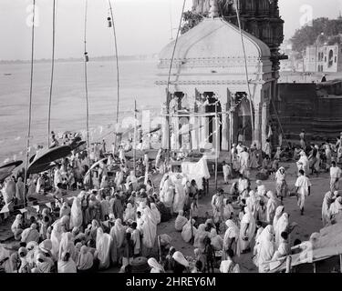 1950s 1960s PEOPLE WORSHIP AT HINDU TEMPLE ON BANK OF GANGES RIVER IN BENARES OR VARANASI INDIA - r19621 PAL001 HARS CONCEPTUAL CITIES FAITHFUL OR BENARES FAITH HINDU HINDUISM INDIAN SUBCONTINENT VARANASI WORSHIP BELIEF BLACK AND WHITE OLD FASHIONED RIVER FRONT SOUTH ASIA Stock Photo