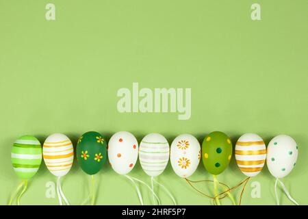 A row of painted multi-colored eggs in a row on a green background. View from above. Place for inscription text. Stock Photo