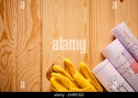 Yellow gloves and rolled drawings on wooden table Stock Photo