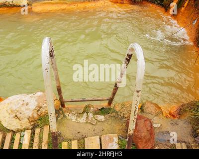 Rusty iron staircase leading to font with muddy mineral water Stock Photo