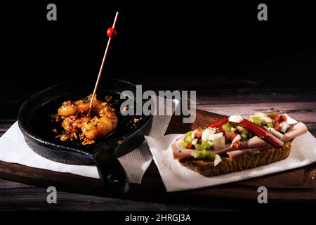 Two different typical Spanish tapas on a rustic table with a dark background. traditional spanish cuisine. Stock Photo