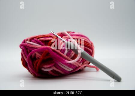 A brightly colored ball of wool with warm colors and a crochet hook Stock Photo