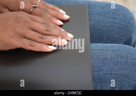 Closeup of an african american woman's hands reading braille in a black book Stock Photo
