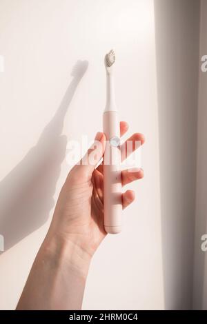 New modern ultrasonic toothbrush in woman hand. Jaw model and dental care supplies. Oral hygiene, dental and gum health, healthy teeth. Dental Stock Photo