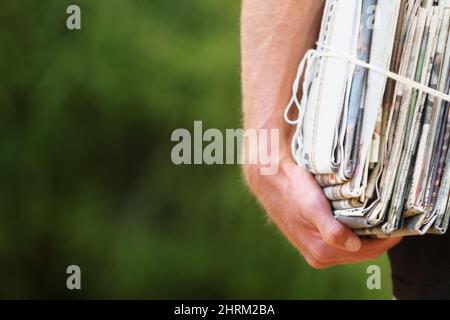 It has to go somewhere.... Shot of a man carrying a bundle of newspapers for recycling. Stock Photo