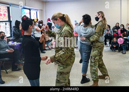 February 5, 2022 - Joint Base McGuire-Dix-Lakehurst, New Jersey, USA: Joint Base McGuire-Dix-Lakehurst, New Jersey, USA - Members of Task Force Liberty dance with Afghan guests during the opening of the Liberty Village Women's Center at Joint Base McGuire-Dix-Lakehurst, New Jersey, Feb. 5, 2022. The Department of Defense, through U.S. Northern Command, and in support of the Department of Homeland Security, is providing transportation, temporary housing, medical screening, and general support for at least 11,000 Afghan evacuees at Liberty Village, in permanent or temporary structures, as quic Stock Photo