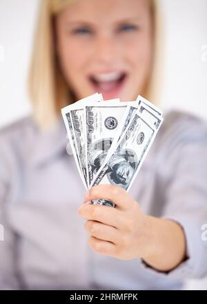 Hard-earned cash. A young woman showing you a wad of cash excitedly. Stock Photo