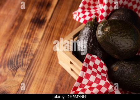 Mexican avocado (persea americana) on rustic wooden table. Main ingredient to prepare guacamole. Close up image with copy space. Stock Photo