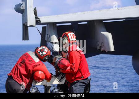 PHILIPPINE SEA (Feb. 24, 2022) Sailors, assigned to the 'Black Aces' of Strike Fighter Squadron (VFA) 41, attach ordnance to an F/A-18F Super Hornet, on the flight deck of the Nimitz-class aircraft carrier USS Abraham Lincoln (CVN 72). Abraham Lincoln Strike Group is on a scheduled deployment in the U.S. 7th Fleet area of operations to enhance interoperability through alliances and partnerships while serving as a ready-response force in support of a free and open Indo-Pacific region. (U.S. Navy photo by Mass Communication Specialist 3rd Class Javier Reyes) Stock Photo