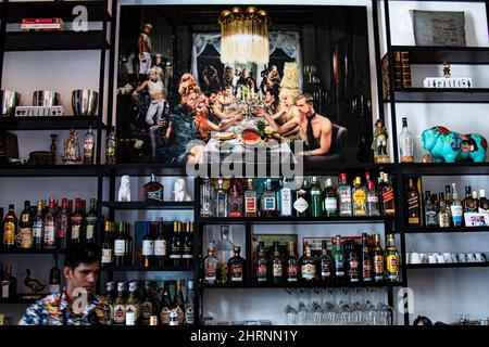 Inside a fancy Cuban restaurant and bar where the bartender is making drinks with alcoholic beverages on display and beautiful mural Cuban artwork. Stock Photo