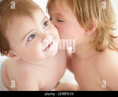 Theres no rivalry between these siblings. Closeup of a sweet little girl giving her baby sister a kiss on the cheek. Stock Photo