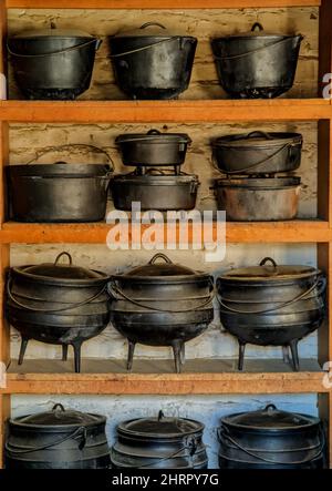 Vertical shot of antique three legged African pots on a wooden shelf Stock Photo