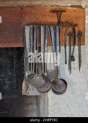 Vertical shot of antique kitchen utensils hanging on a wall Stock Photo