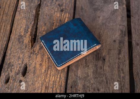 Leather navy blue with white cream wallet handmade working on wood background, Genuine vegetable tanned leather Stock Photo