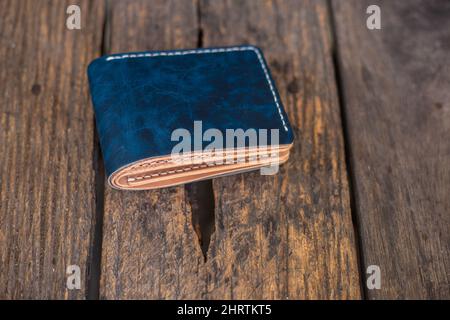 Leather navy blue with white cream wallet handmade working on wood background, Genuine vegetable tanned leather Stock Photo