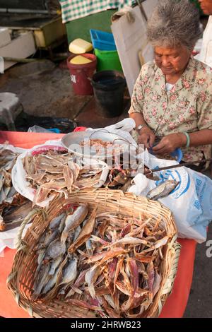 A woman peels dried shrimp while selling other dried fish at the waterfront of Cheung Chau, an Outlying Island of Hong Kong's New Territories Stock Photo