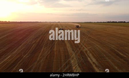 Truck loaded with haystacks drives up to tractor to load haystack Stock Photo